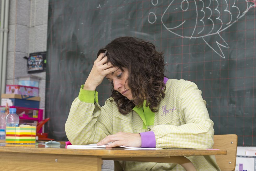 Erschöpfte Lehrerin sitzt vor Wandtafel